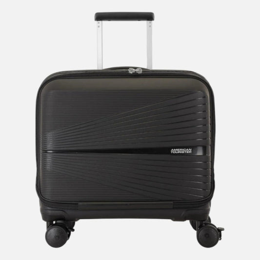 A black American Tourister carry-on suitcase with a textured, diagonally ribbed exterior, featuring an extended telescoping handle and four spinner wheels, shown against a plain white background.